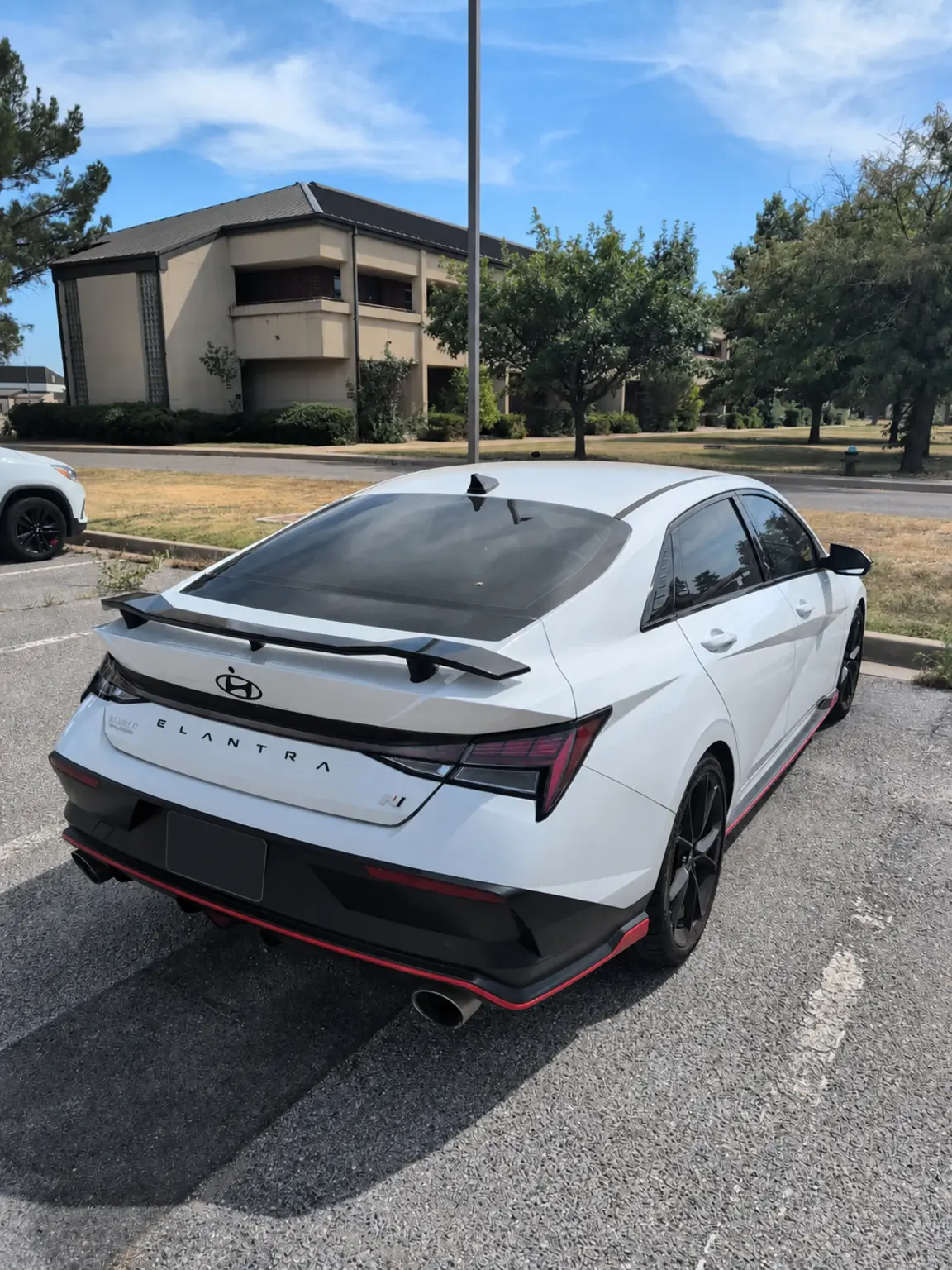 Rear three-quarter view with factory wing and diffuser; license plate redacted
